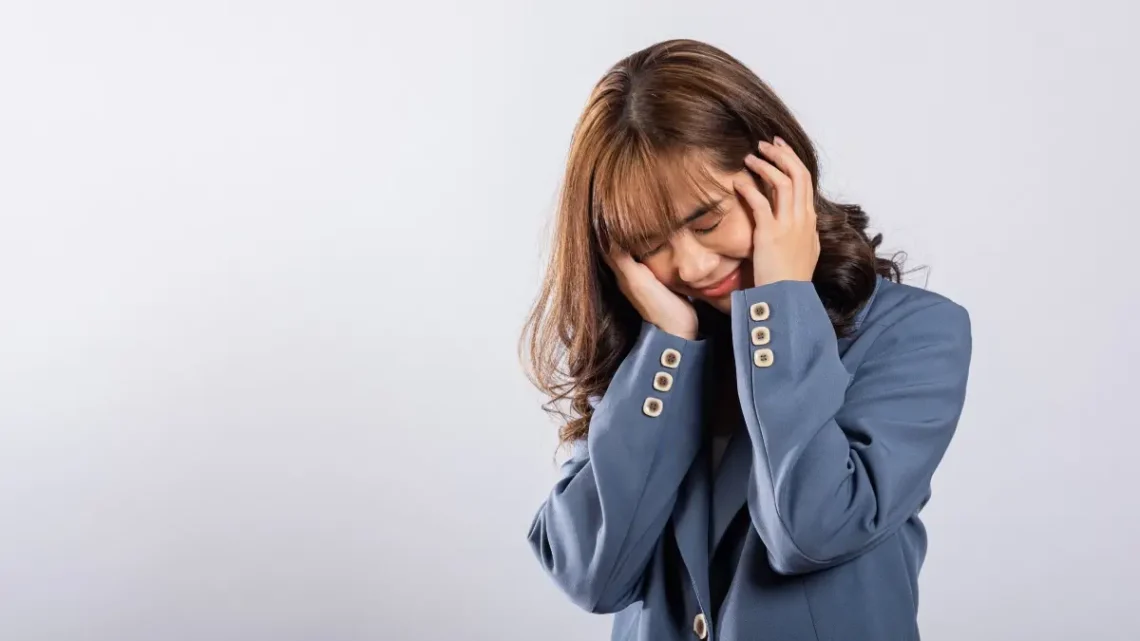Femme hypersensible tenant sa tête avec les mains, expression de fatigue et de surcharge mentale